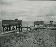 Latrines militaires « de marée », conçues pour rester au-dessus de l'eau à marée basse, pour que les matières fécales soient toujours dispersées par la mer (probablement durant la 2nde guerre mondiale). (source : Archives médicales militaires des États-Unis)