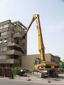 Démolition d'un immeuble par un engin de chantier.