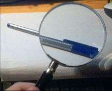 Une loupe, grossissant l'image d'un stylo.