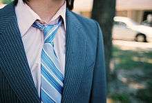 Une cravate bleue, portée sur une chemise et avec une veste.