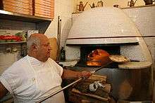 Enfournement d'une pizza dans un four à bois à Naples