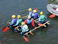 儿童乘座自制的筏在水面上航行。
